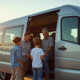 Famille inspectant un van 7 places dans un concessionnaire ensoleille