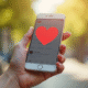 Main d'une jeune femme tenant un smartphone avec notification de coeur